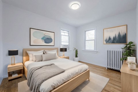 A bedroom with a large bed, a nightstand with a lamp, and a plant on the side table. at 83-85 Silver Birch, Toronto Canada